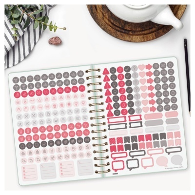 Caderno aberto com folhas de autocolantes organizacionais em rosa, vermelho e cinza