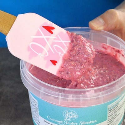 Colher de silicone rosa com mistura de frutas silvestres num recipiente plástico