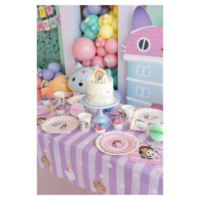 Mesa de festa infantil com decoração de menina e gato, bolo com arco-íris, cupcakes, balões coloridos e toalha lilás às riscas.