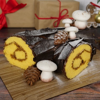 Bolo formato tronco com cobertura de chocolate e decoração de cogumelos e pinhas de chocolate