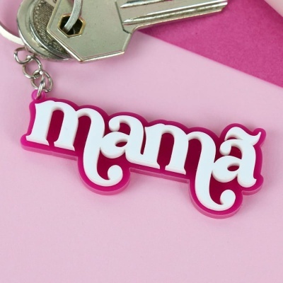 Chaveiro com a palavra mama em letras brancas sobre fundo rosa, junto de duas chaves metálicas