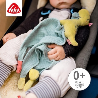 Bebé com brinquedo de peluche e pano azul sentado numa cadeira