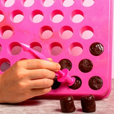 Forma rosa de silicone para chocolates com moldes redondos e ferramenta rosa a retirar bombons escuros