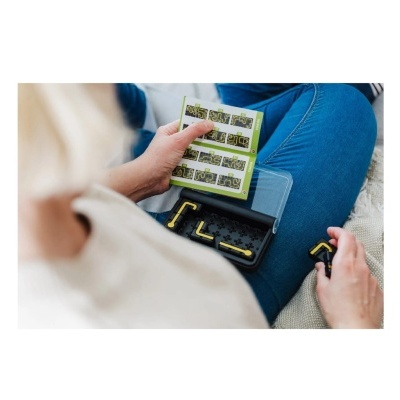 Pessoa sentada segurando caixa preta com ferramentas amarelas e manual colorido