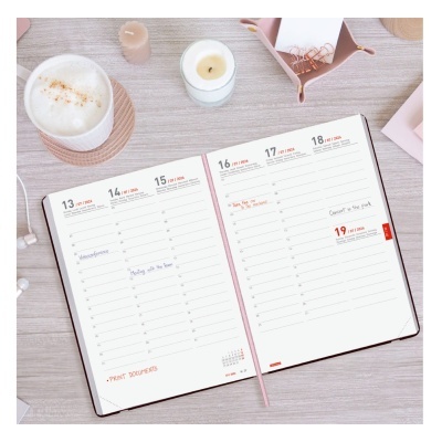 Agenda semanal aberta com datas de março, mesa clara, bebida, vela e clipes