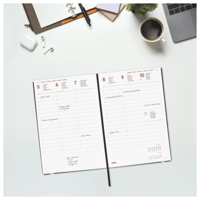 Planner semanal aberto com datas, caneta e acessórios de escritório