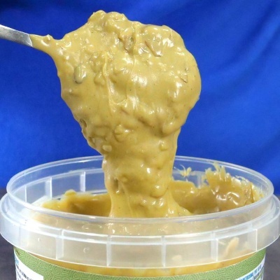 Pasta castanha cremosa sendo retirada de recipiente plástico