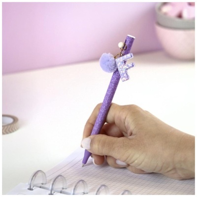 Caneta roxa com pendente em forma de letra F e pompom