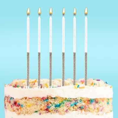 Bolo de aniversário com velas acesas e bolinhas coloridas no interior