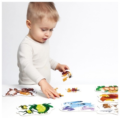Criança a montar puzzles de animais coloridos numa mesa branca