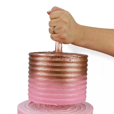 Bolo redondo com cobertura cobre e rosa segurado por uma mão