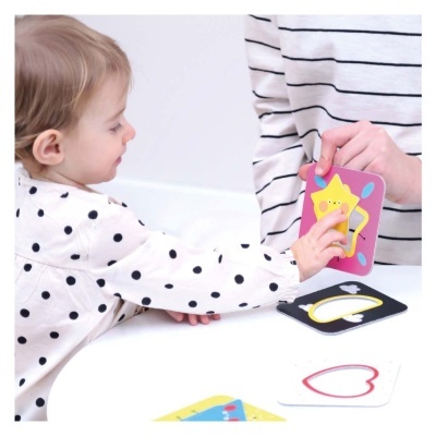 Cartas educativas coloridas com estrela amarela em fundo rosa e outras formas, usadas por criança e adulto