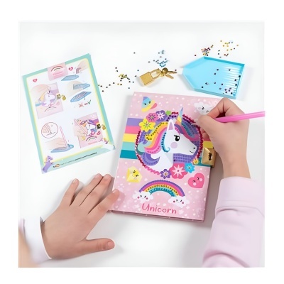 Caderno rosa de unicórnio sendo decorado por criança com marcador cor de rosa