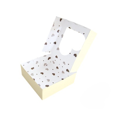 Caixa aberta em cartão amarelo com padrão de corações no interior e janela em forma de coração na tampa