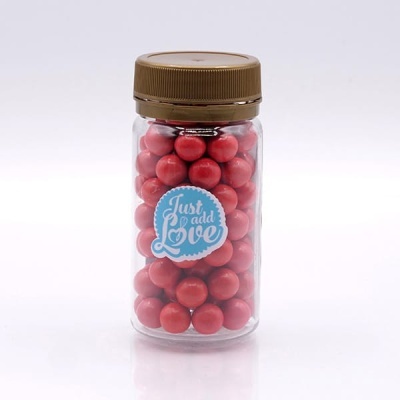 frasco transparente com esferas vermelhas e etiqueta azul 'Just add Love'