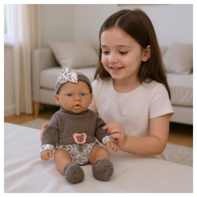 Boneca bebé vestida com camisola castanha de malha e faixa de cabeça branca com padrão floral