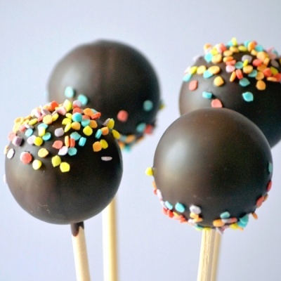 Cake pops de chocolate preto com granulado colorido em paus de madeira