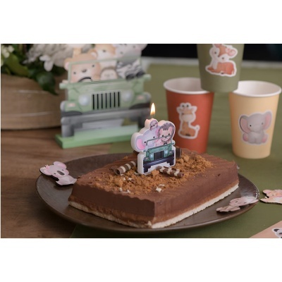 Bolo de chocolate decorado com vela com desenho de jipe e animais, copos de papel com imagens de animais e decoração de safari