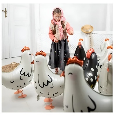 Criança entre balões de galinha brancos e pretos num espaço interior claro