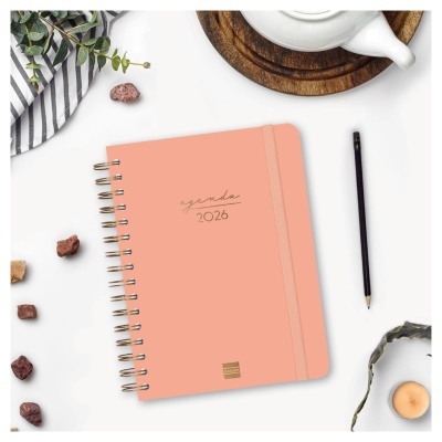 Agenda 2026 com capa dura cor de salmão, lápis preto e bule branco