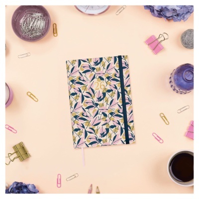 Agenda floral com número 26 e acessórios de escritório num fundo rosa