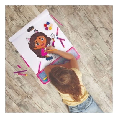 Criança a colorir desenho com lápis e tintas no chão de madeira clara