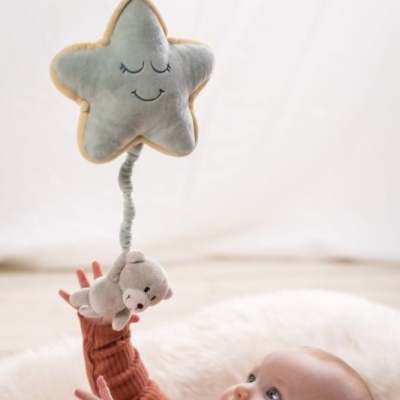 Móbile de pelúcia com estrela cinzenta e urso pendurado sobre um bebé