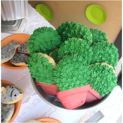 Bolinhos decorativos verdes em forma de plantas e bolinhos cinzentos em pratos laranja.