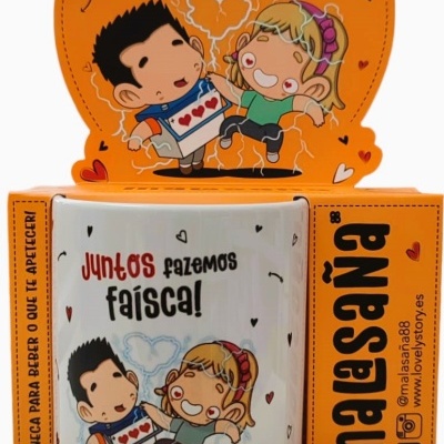 Caneca branca decorada com ilustração e texto 'Juntos fazemos faísca!' em suporte com embalagem laranja
