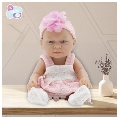 Boneca bebé com roupa de croché rosa e branca e faixa de cabeça com flor