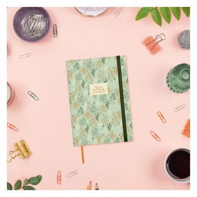 Agenda 2026 com padrão de folhas, clips, prendedores e café sobre fundo rosa