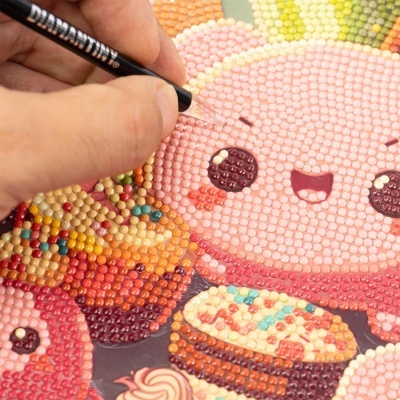 Figura fofa rosa feita com pintura em diamante com cupcakes coloridos e texturas brilhantes.