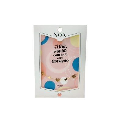 Pulseira dourada com laço e corações numa embalagem branca com fundo rosa pontilhado