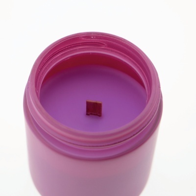 Vela roxa num frasco de vidro com pavio de madeira