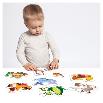 Criança a montar puzzles de animais coloridos em tabela branca