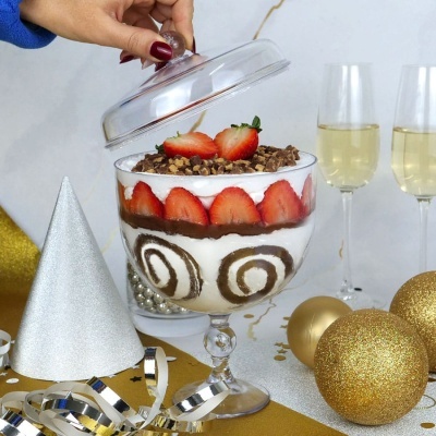 Taça de sobremesa com morangos e chocolate em ambiente festivo.