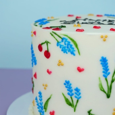 Bolo decorado com flores e frutas vermelhas em glacê branco