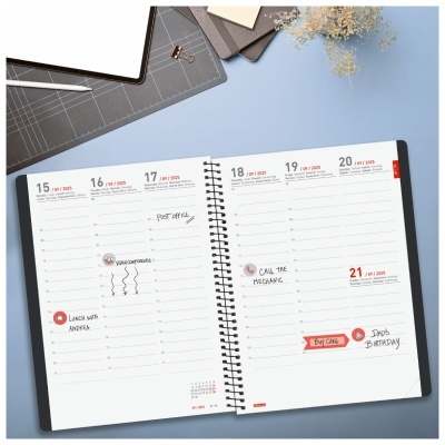 Agenda semanal aberta com anotações e utensílios de escritório sobre mesa azul