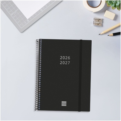Agenda preta com texto 2026 2027 e material de escritório sobre mesa clara