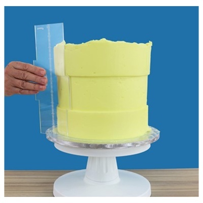 Bolo com creme amarelo claro em suporte branco de madeira com régua transparente ao lado