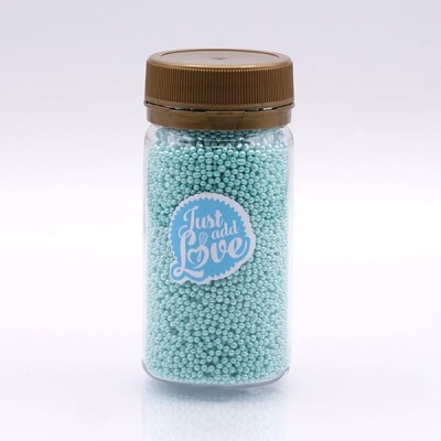 Frasco com pérolas azuis e tampa castanha com etiqueta 'Just add Love'