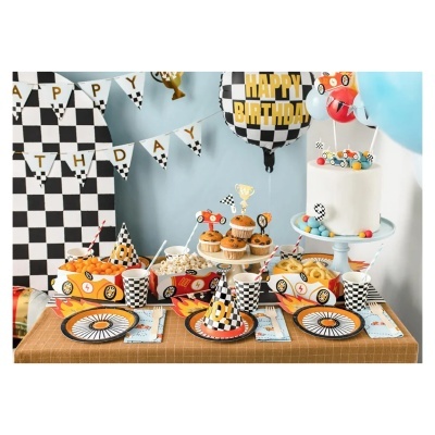 Mesa decorada para festa de aniversário com tema de corridas, chapéus, balões, pratos, copos e comida.