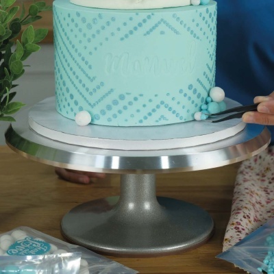 Bolo azul claro decorado com padrão de bolinhas azuis e esferas decorativas brancas e azuis