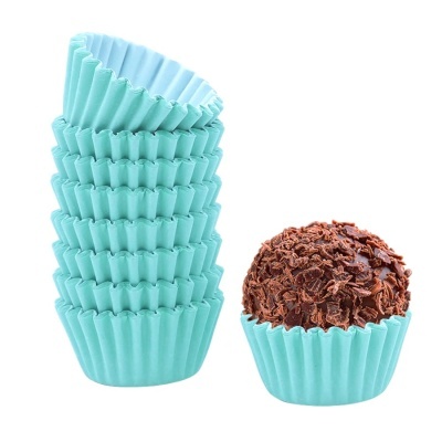 Forminhas de papel azul-turquesa empilhadas e brigadeiro com lascas de chocolate.