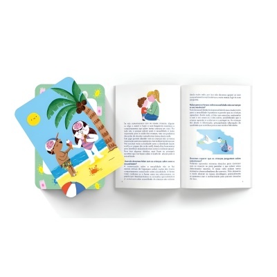 Cartas coloridas infantis ao lado de livro aberto com texto em português e ilustrações de crianças.