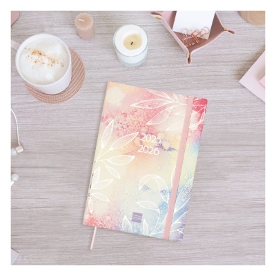 Agenda decorada com padrão floral em tons pastel e os anos 2025 2026 na capa sobre mesa de madeira clara