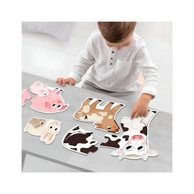 Menino a montar puzzle de animais de quinta coloridos sobre mesa cinzenta