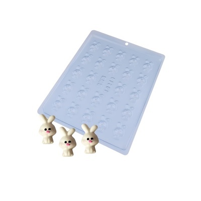 Forma de silicone azul com moldes de coelhos e três doces em forma de coelhos brancos