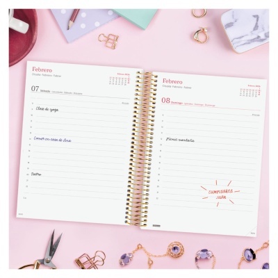 Agenda diária aberta nas datas de 7 e 8 de fevereiro sobre fundo rosa com acessórios dourados e lilás