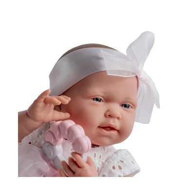 Boneca de bebé realista com fita branca e vestido branco segurando um chocalho rosa.